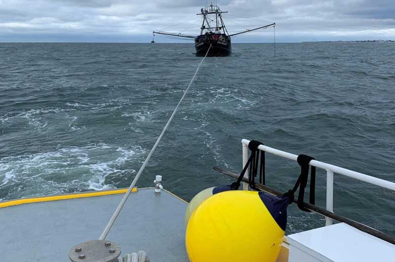 Commercial fishing boat who is a commercial boat towing being being towed by a Sea Tow boat.